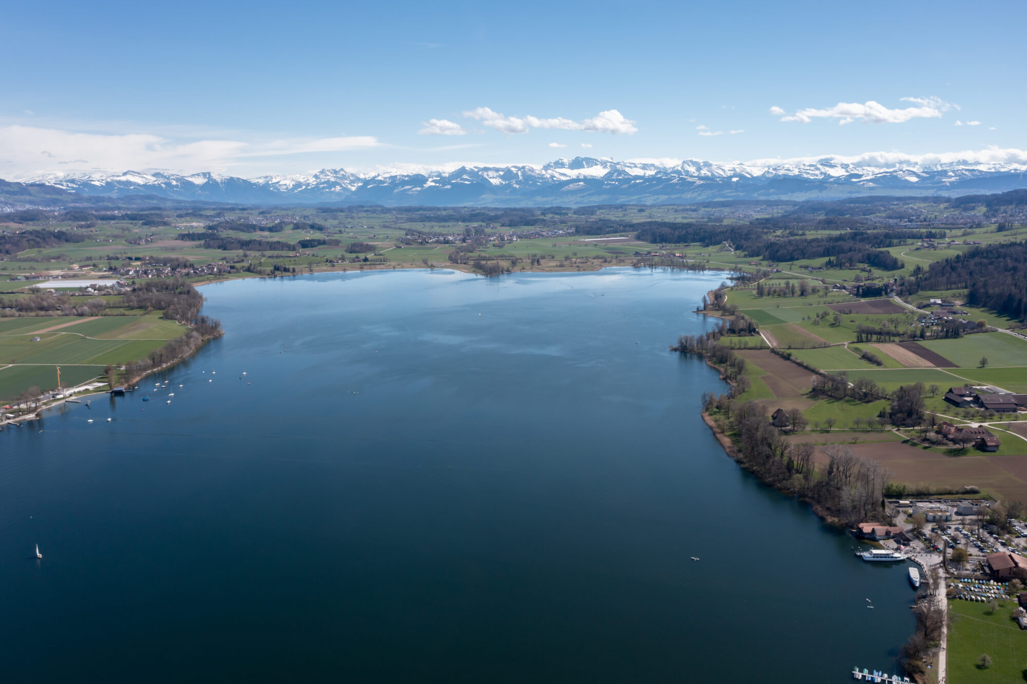 Veduta aerea del lago Greifensee in primo piano e delle montagne innevate delle Alpi sullo sfondo, Zurigo, Svizzera